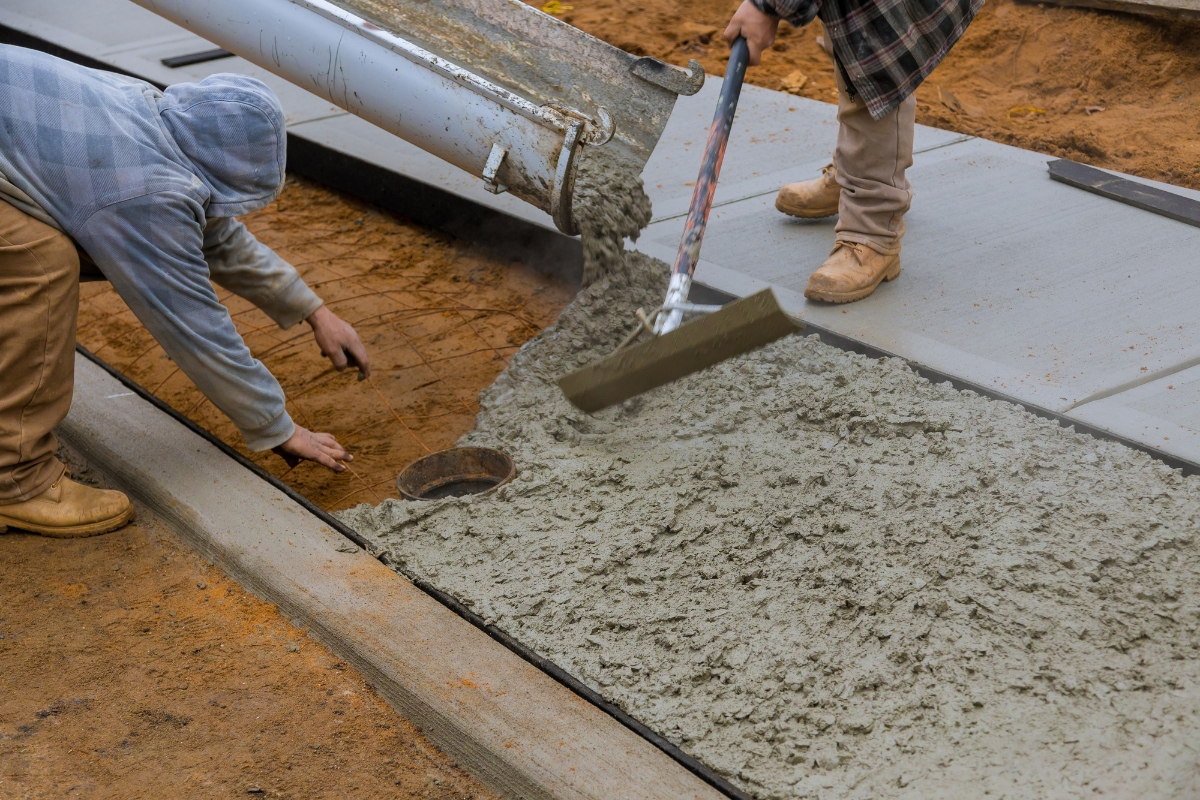 Crew members involved in Concrete Construction, shaping a new concrete pathway.