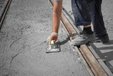 Worker using tools to flatten and finish new concrete pavement.