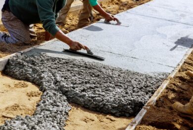 Workers using tools for Concrete Construction as they form the surface of a fresh walkway.