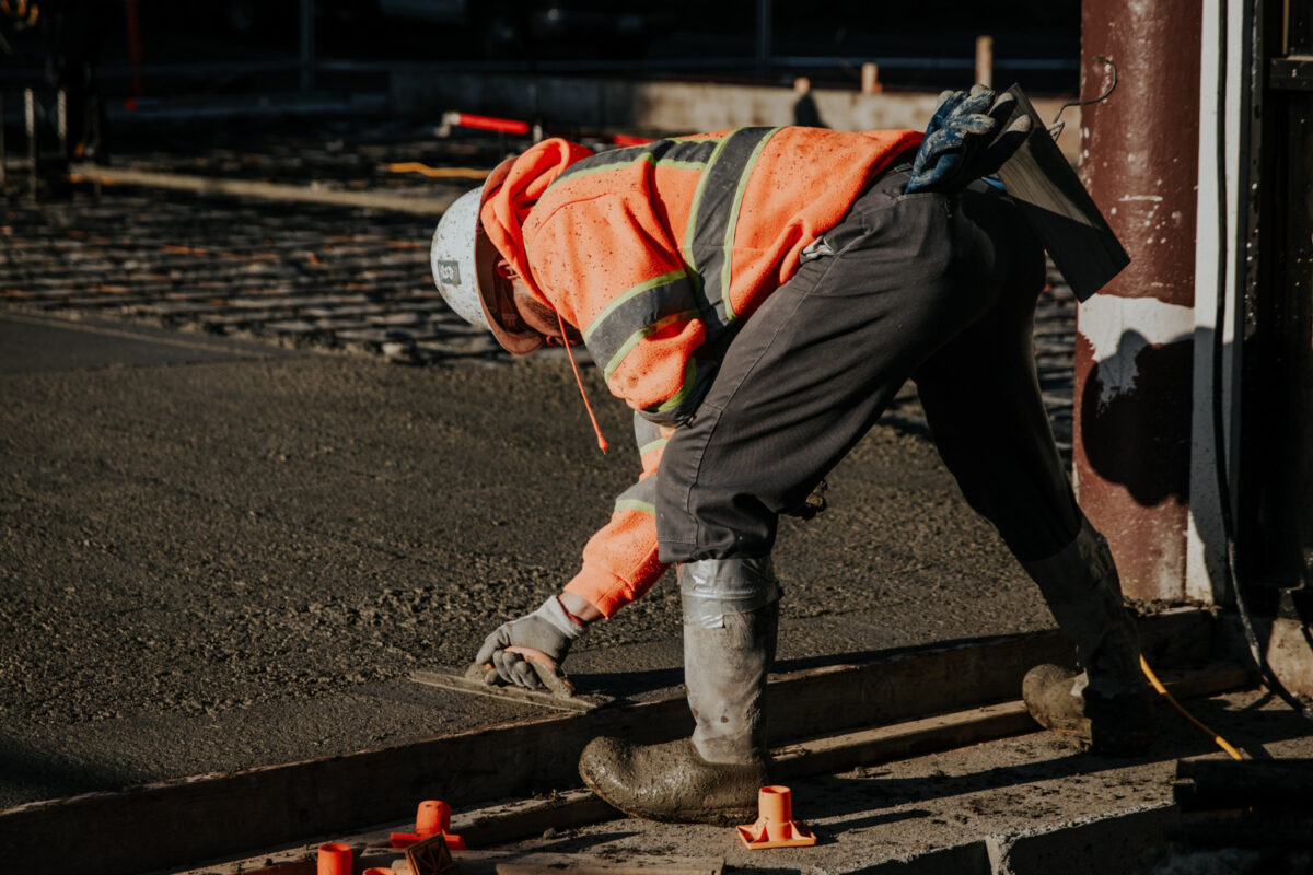 Construction worker leveling freshly poured concrete