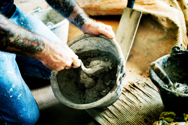 Worker mixing cement in a bucket with a trowel